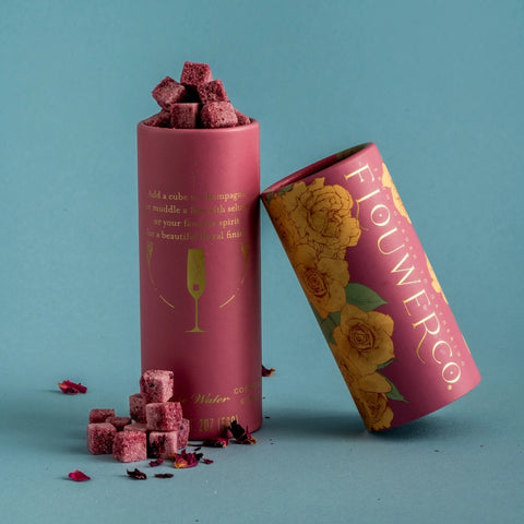 Rose cocktail cubes sitting by their pink paper tube packaging
