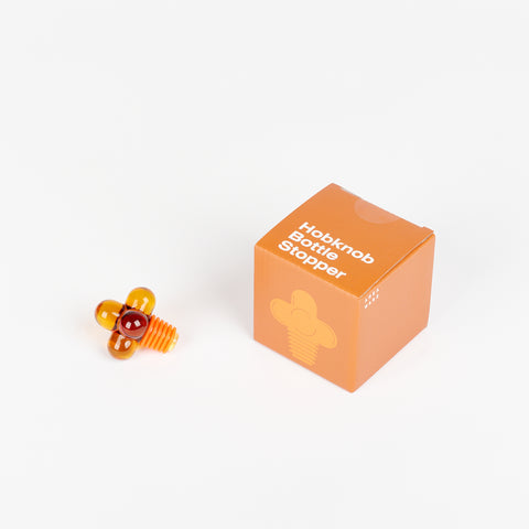 Amber Areaware Hobknob Bottle Stopper with orange box beside it
