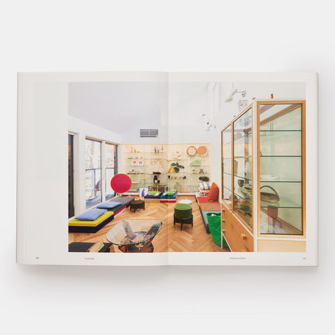a small living room space with colorful cushions and glass display cases shown in an open book Japanese Interiors