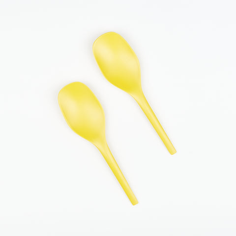two lemon yellow serving spoons side by side at an angle