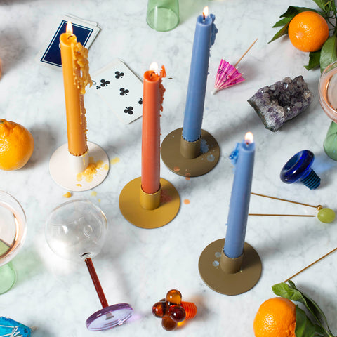 a marble top table with lit candles, a tipped over wine glass, a tangerine, cocktail picks, and playing cards