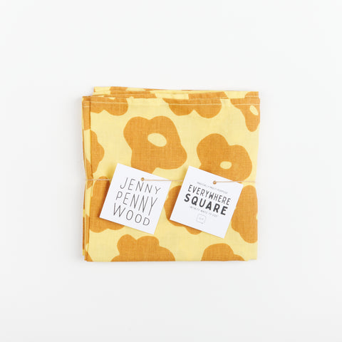Folded yellow Jenny Pennywood Everywhere Square with an orange flower abstract pattern.