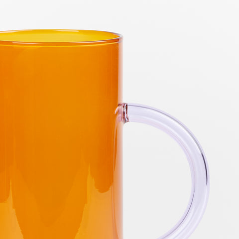 a close of detail of orange amber glass vase with lilac side handle