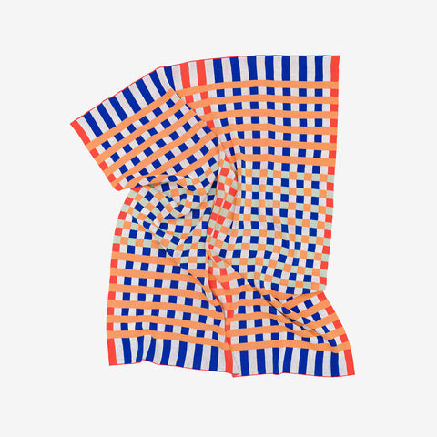 Verloop cotton knit throw with checkerboard pattern in poppy and cobalt showing wrinkled texture