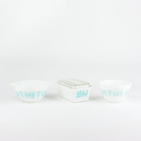 three vintage white pyrex serving dishes with pale blue decorative wrap around design