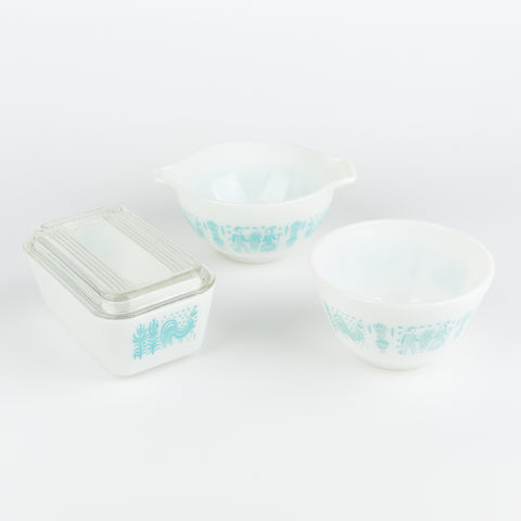 top down view of three vintage white pyrex serving dishes with pale blue farm themed decorative wrap around design