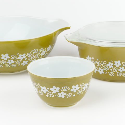 Avocado colored green pyrex serving bowls in varying sizes with a white floral wrap around pattern