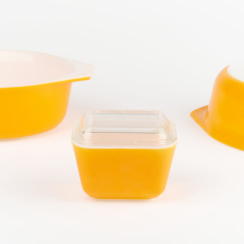 detail of a bright yellowy orange pyrex container with a glass lid
