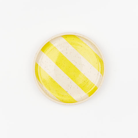 A single ceramic side place with a speckled surface and yellow stripes