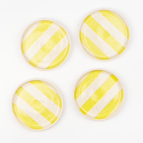A set of four ceramic striped coupe plates with yellow stripes