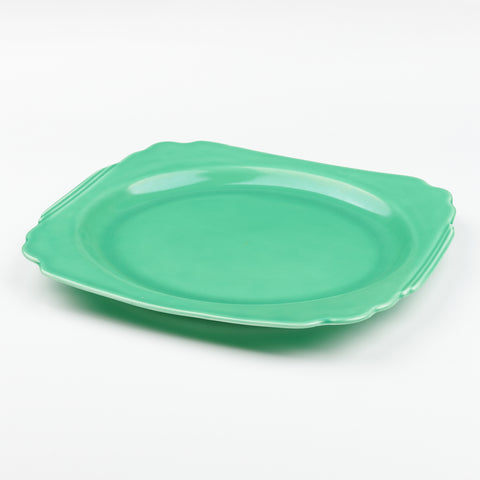a green ceramic serving platter with scalloped edges
