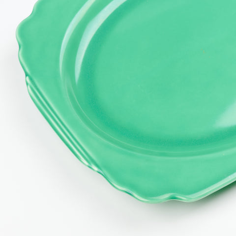a close up of a green vintage serving platter with curved edges