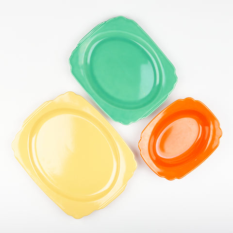 Three artfully arranged ceramic serving platters of varying sizes in three colors yellow green and red
