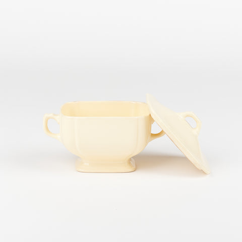 off-white ceramic riviera ware sugar dish with lid taken off and leaning against the dish