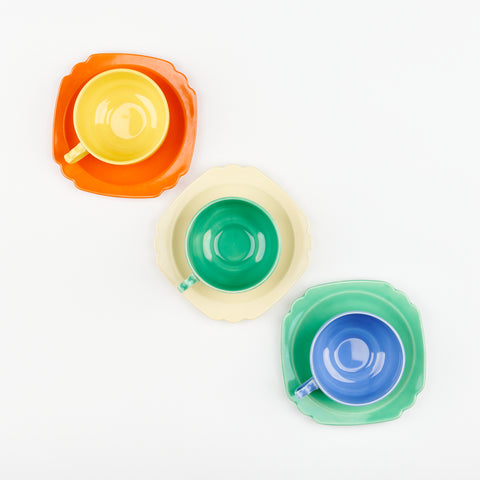 top down view of three colorful coffee cups on artfully mismatched saucers