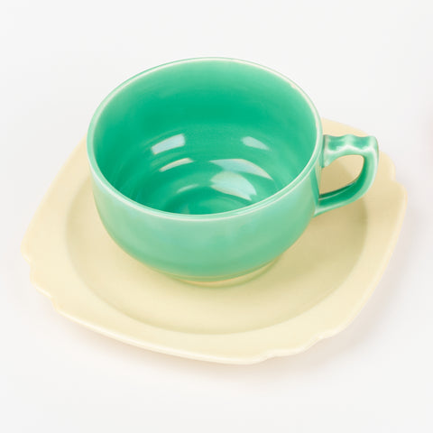 A green Riviera Ware ceramic mug on a yellow saucer plate