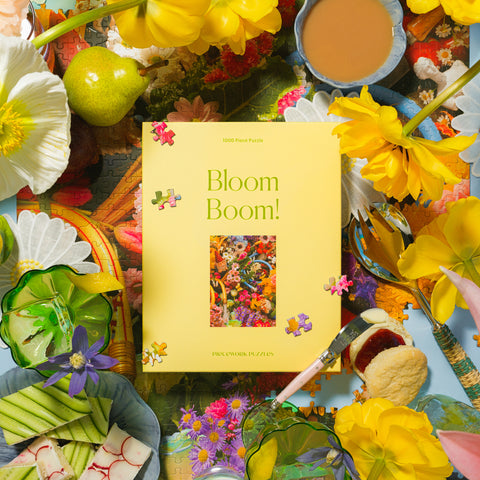 Yellow Bloom Boom Piecework Puzzle 1000 piece puzzle box surrounded by flowers, fruit, and finger sandwiches