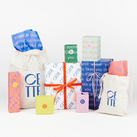 Several CETTE custom gift wrapped packages and gift bags shown together on a white background