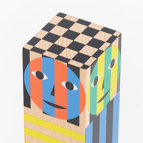 detail of the top of an areaware grinder with checkerboard pattern on top and colorful faces made out of shapes