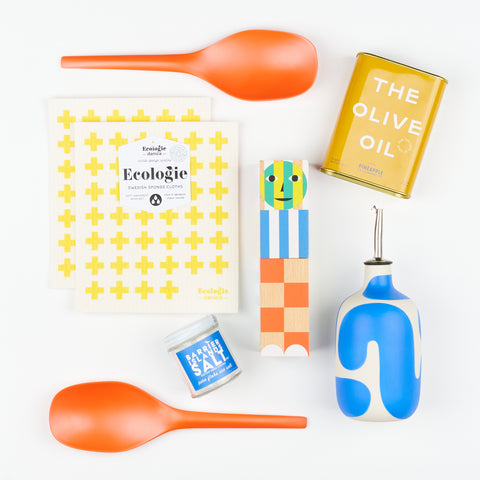 two Ecologie Swedish dish cloths, two EKOBO serving spoons, a Franca oil cruet, an Areaware Everybody Grinder, a jar of Barrier Islands flake salt and a tin of Pineapple Collaborative olive oil