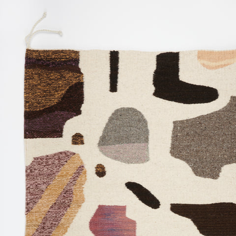 detail of a handwoven rug with a design of earth-toned stones
