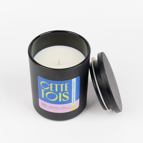 an open view of CETTE FOIS a scented soy wax candle in a black jar with the lid leaning on the side and scent notes of Grapefruit, Thyme, and Bergamot