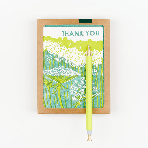 A yellow Papier wiggle top pen sitting on top of a box of thank you cards with an illustration of Queen Anne's Lace