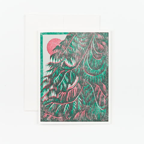 A hand printed holiday card with an illustration of a cedar tree and a sun rising in the background