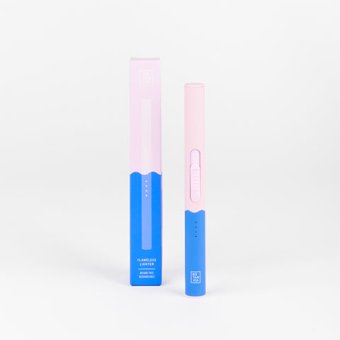 A Botanica Duo Tone Flameless lighter next to the box that it comes in with two color tones lavender and blue