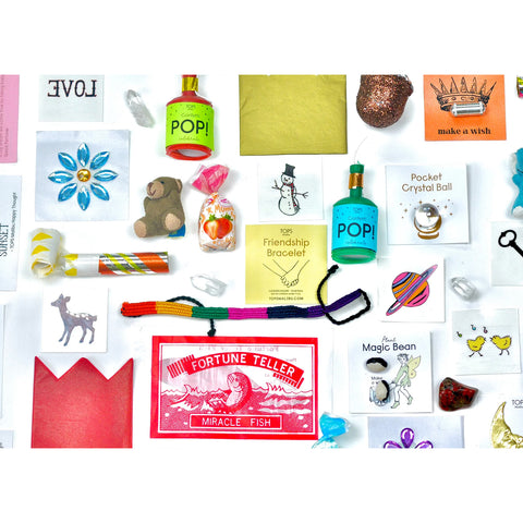 a selection of potential prizes that come inside a TOPS Malibu surprise ball including confetti, a friendship bracelet, stickers and more