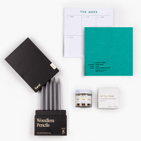 Clarity Kit gift set with teal Case Study weekly planner, Karst woodless pencils, and Madison + Green aromatherapy jar arranged flat on white background.