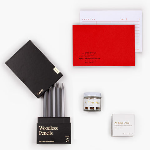 Clarity Kit gift set with red Case Study list notepad, Karst woodless pencils, and Madison + Green aromatherapy jar arranged flat on white background.