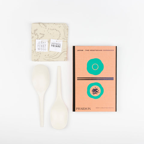 A Cookbook set including white EKOBO bamboo serving spoons, Phaidon Cookbook -Japan: The Vegetarian Cookbook, and a Jenny Pennywood Everywhere Square in natural and fog