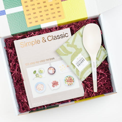 An open Cette gift box showing A Cookbook set including EKOBO bamboo serving spoons in stone color, Phaidon Cookbook - Simple and Classic 123 step by step recipies, and a Jenny Pennywood Everywhere Square in sage and matcha