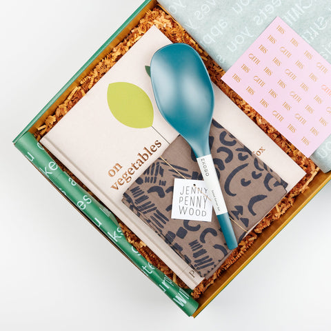 an open Cette Gift Box showing Blue Abyss EKOBO bamboo serving spoons, Phaidon Cookbook - On Vegetables by Jeremy Fox, and a Jenny Pennywood Everywhere Square in walnut and midnight