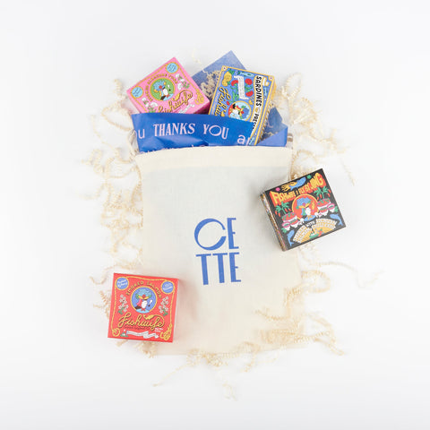 A Cette drawstring gift bag with blue tissue paper and four boxes of Fishwife tinned fish