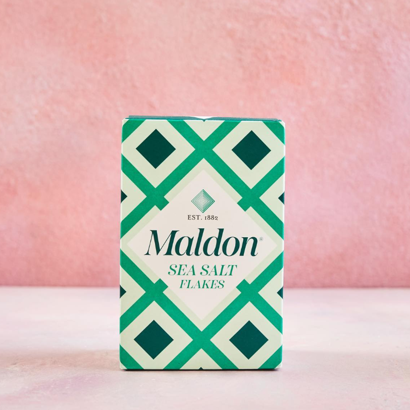 Maldon sea salt flakes green patterned box on a pink background, part of the Perfect Balance gift set.