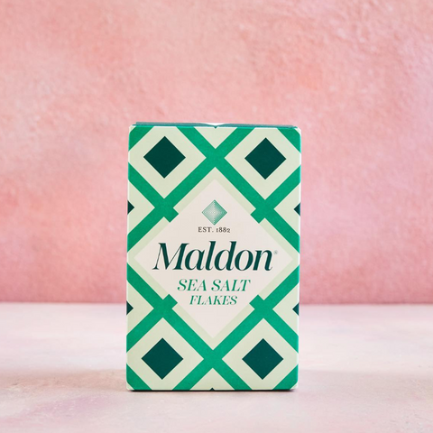 Maldon sea salt flakes green patterned box on a pink background, part of the Perfect Balance gift set.