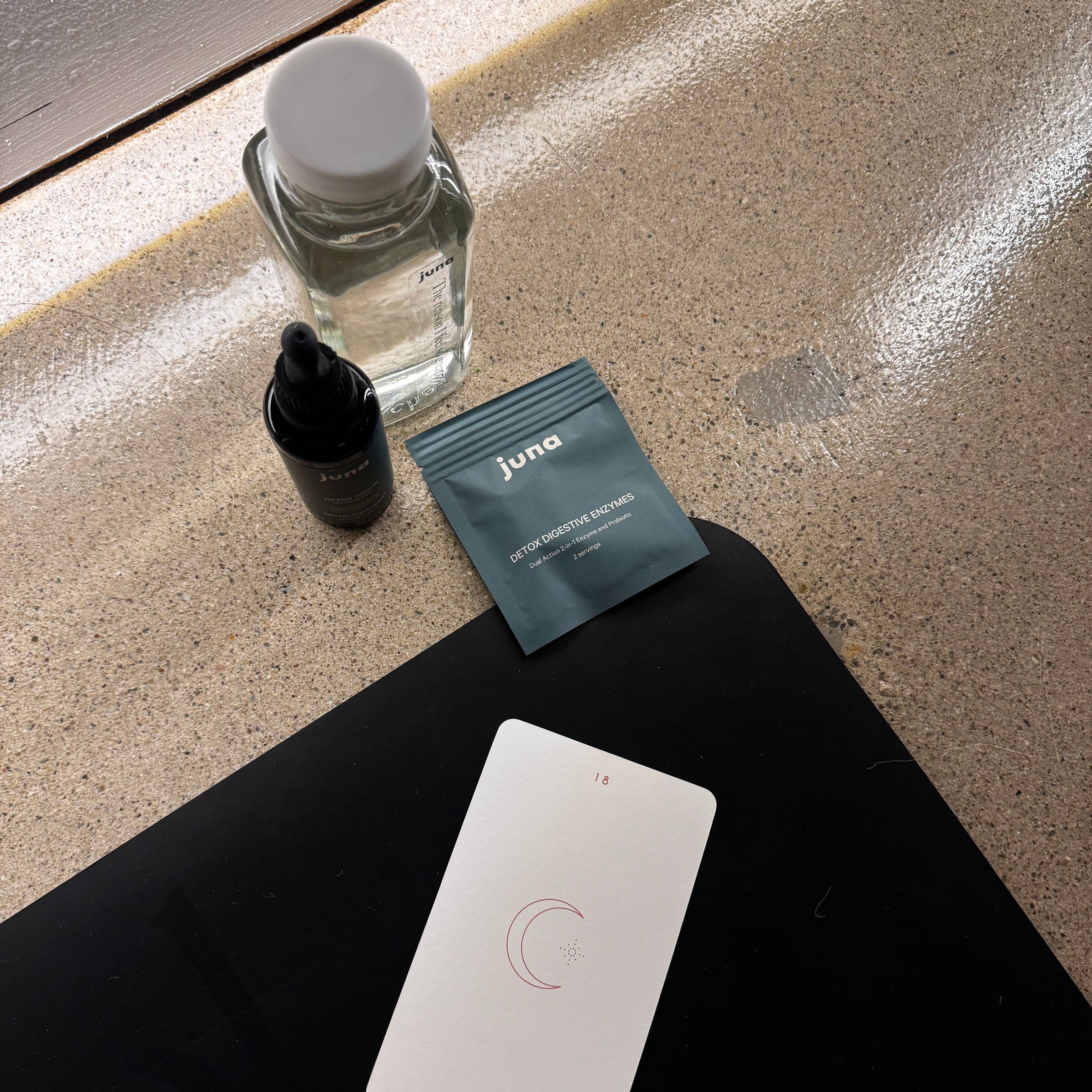 Product items including a bottle, packets, and card on a textured surface