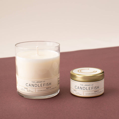 Candlefish full-size glass candle and travel tin candle on brown background. Tin included in the Kindled Comfort gift set.
