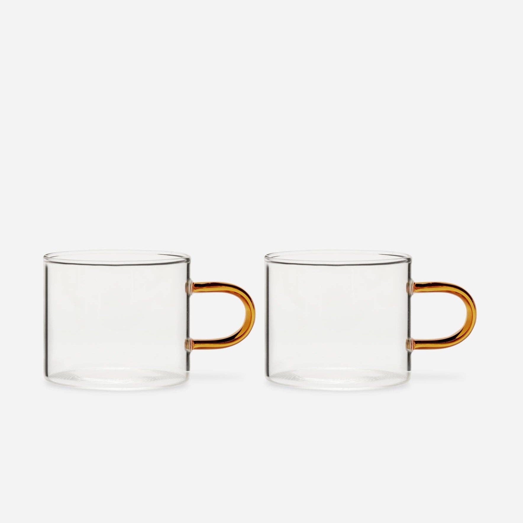 Two clear glass mugs with amber handles on a white background included in the Steep Dreams gift set.