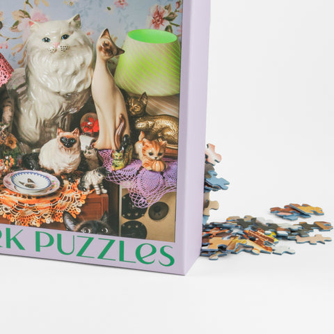 Close up of Cat Person puzzles with cats on the the box with puzzle pieces falling out of the box