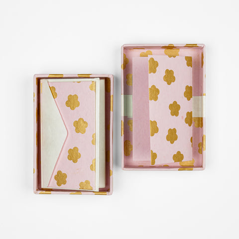 Open box of pink cards with a gold flower pattern