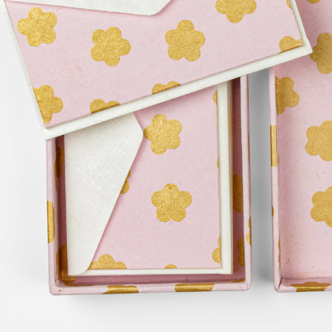 Pink cards with gold flower details in their box