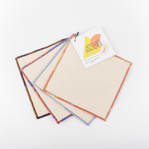 Ivory napkins with mixed orange, blue, red, brown and blue edges by Atelier Saucier