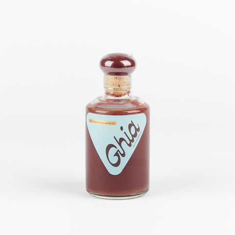 Small glass bottle of Ghia Aperifit with red liquid and pale blue triangular shaped label 