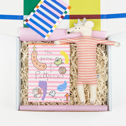 a children's gift box with the book The Game of Patterns and a stuff animal mouse with a pink striped body and a silver crown