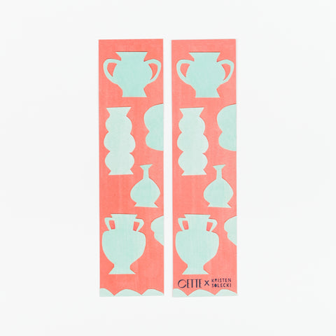 The front and back of two artist designed red bookmarks with light green vases on them