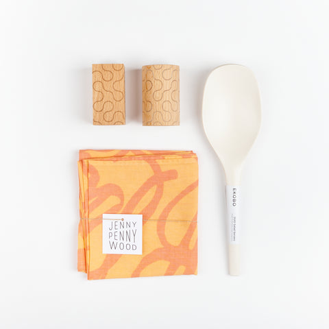 Areaware Pattern Salt and Pepper Shakers, a set of white EKOBO Bamboo serving spoons, and a melon and tangerine colored abstract patterned Jenny Pennywood cotton linen Everywhere Square