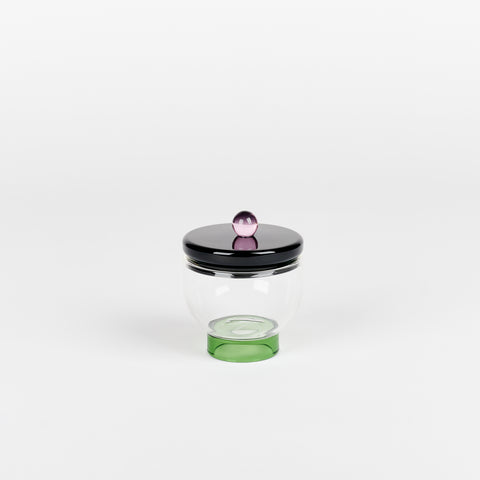 an Areaware Sophie Lou Jacobsen small glass salt bowl with a green footed base a black lid with a round lilac ball on top